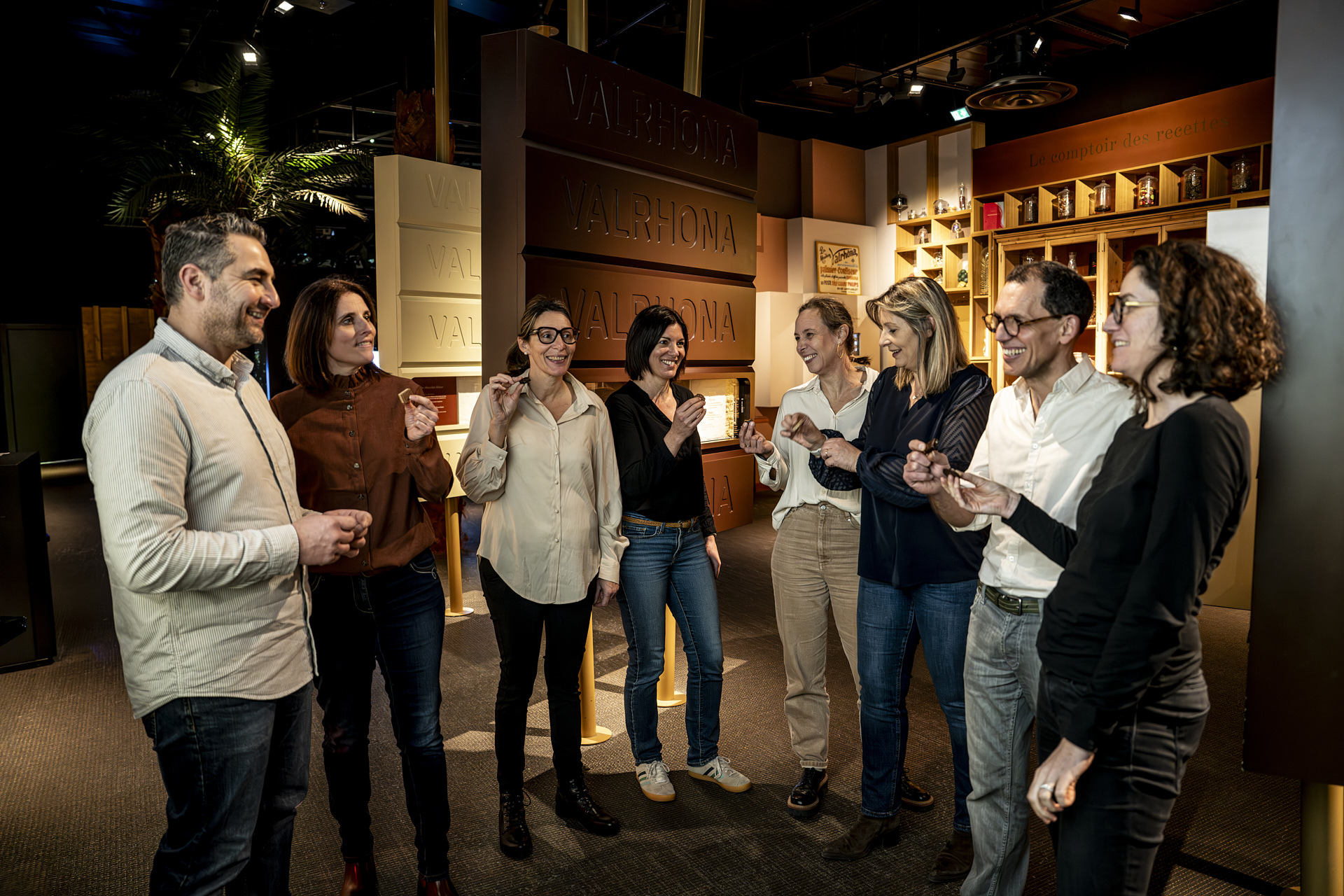 Photo officielle d’un groupe de visiteurs adultes dégustant du chocolat dans le parcours de la Cité du Chocolat Valrhona.